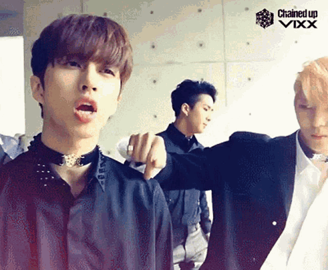 a group of young men are standing next to each other with a chained up vixx logo behind them