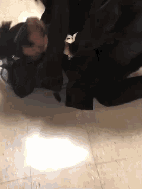 a man in a black jacket is laying on the floor with his head on the ground .