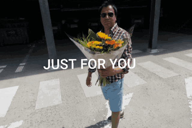 a man holding a bouquet of flowers in front of a sign that says " just for you "