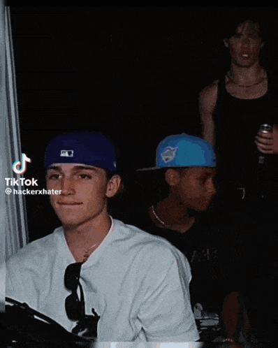 a man wearing a purple hat is sitting in a dark room with other people