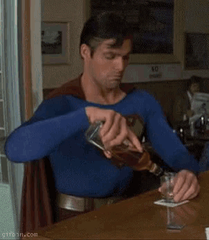 superman is sitting at a table with a bottle of whiskey