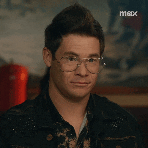 a close up of a man wearing glasses with the max logo in the background