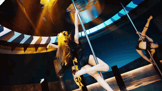 a woman in a black dress is dancing on a pole in front of a mirror