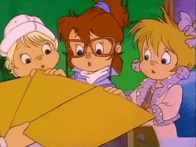 a group of three alvin and the chipmunks are looking at a piece of paper .