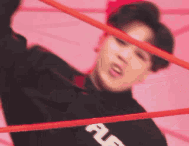 a man is standing in a boxing ring with a red rope .