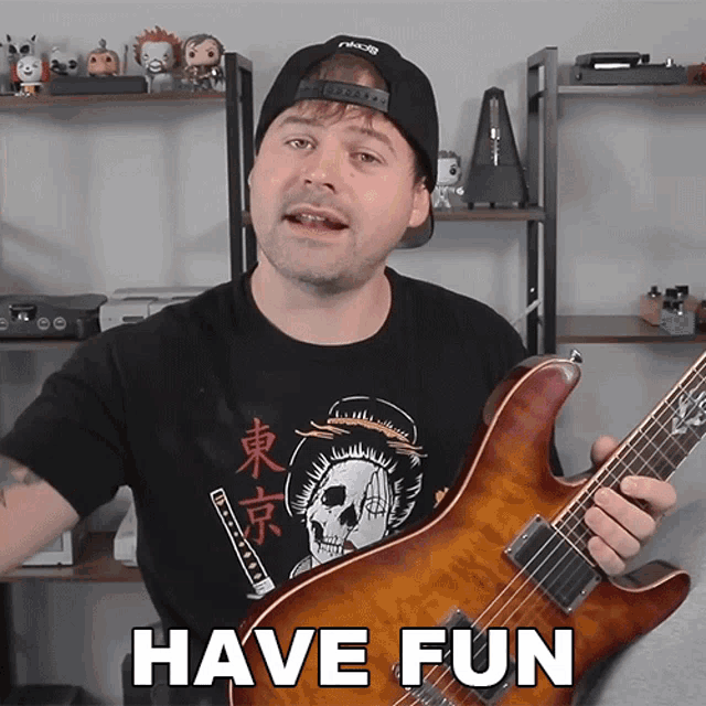 a man is holding a guitar in front of a sign that says " have fun "