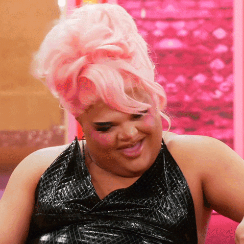 a woman with pink hair is smiling and wearing a black dress