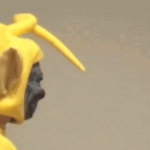 a close up of a statue of a gorilla wearing a yellow hat with long beak .