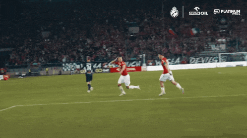 a group of soccer players are running on a field with an ad for platinum in the background