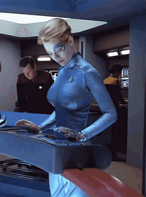 a woman in a blue uniform with a star trek emblem on her chest