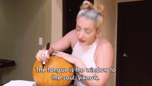 a woman is carving a pumpkin with the words the tongue is the window to the soul y know