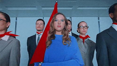 a woman in a blue dress stands in front of a group of people