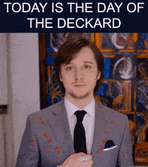 a man in a suit and tie is standing in front of a sign that says today is the day of deckard