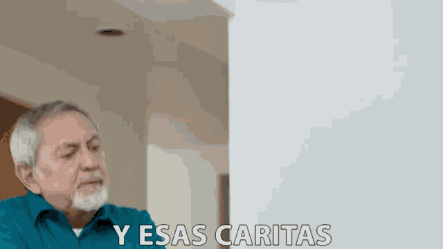 a man in a blue shirt says " y esas caritas " in front of a white wall