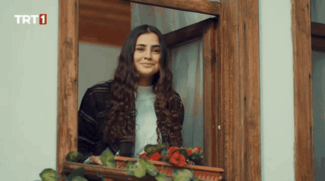 a woman looks out of a window with trt1 on the bottom