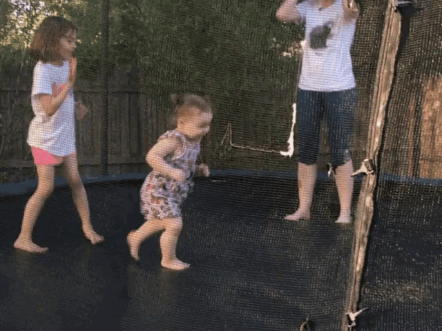 a little girl wearing a t-shirt that says ice is playing on a trampoline
