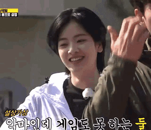 a woman is smiling while a man applauds her in korean