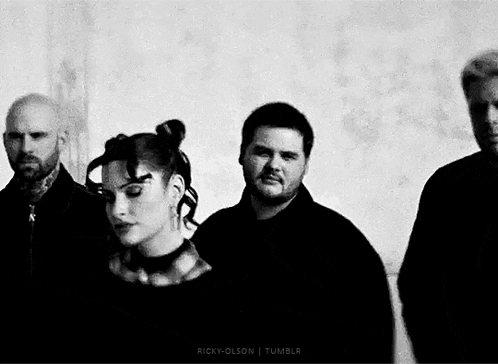 a black and white photo of a group of people standing next to each other in front of a wall .