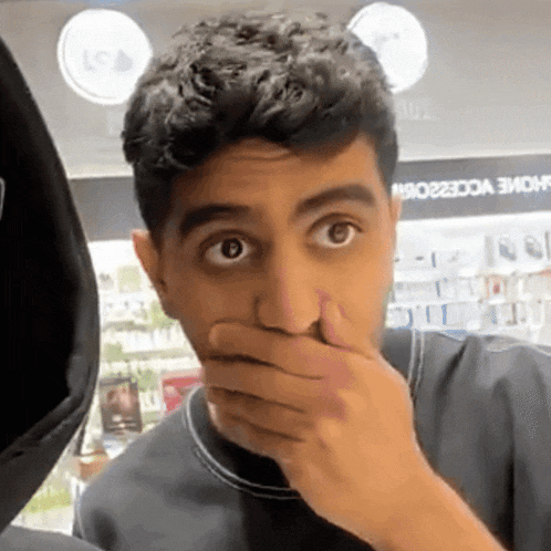 a man covering his mouth with his hand in front of a store that says home accessories