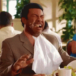 a man in a suit is laughing with a napkin around his neck .
