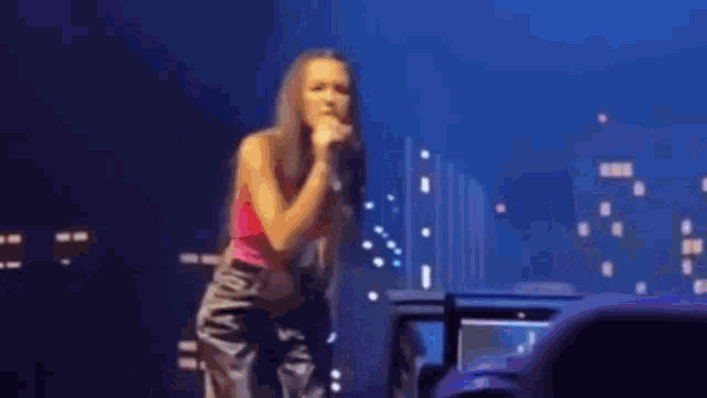 a woman is singing into a microphone on stage .