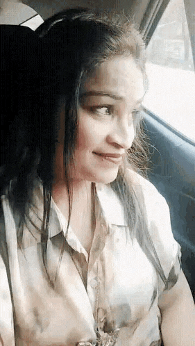a woman is sitting in the back seat of a car and smiling .