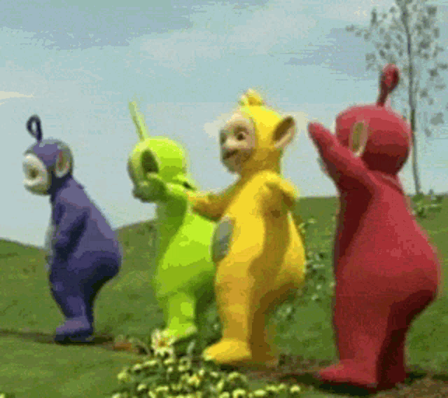 a group of teletubbies standing in a grassy field