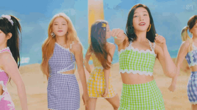 a woman in a green and white dress is dancing on a beach with other women .