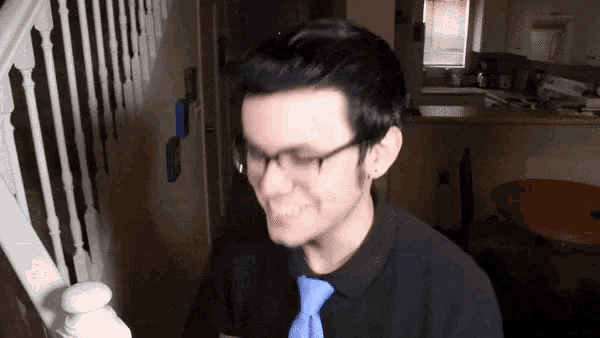 a man wearing glasses and a blue tie is smiling in a kitchen