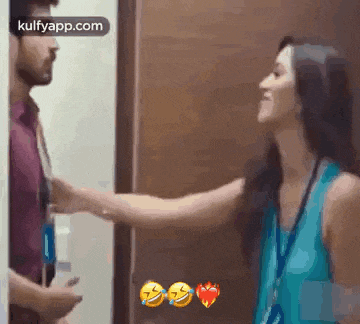 a man and a woman are standing next to each other in a room and the woman is touching the man 's arm .