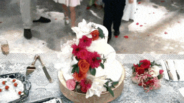 a wedding cake is sitting on a table with flowers