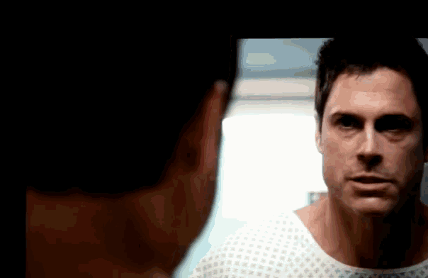 a man in a hospital gown looks at another man in a mirror