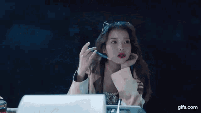 a woman is sitting at a desk with a pen in her hand and a cigarette in her mouth .