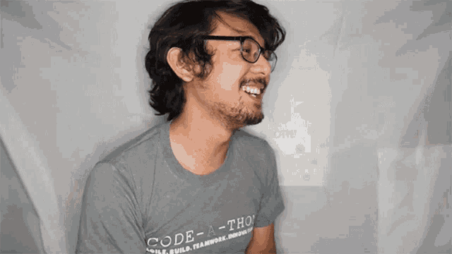 a man wearing glasses and a gray shirt that says code-a-thon