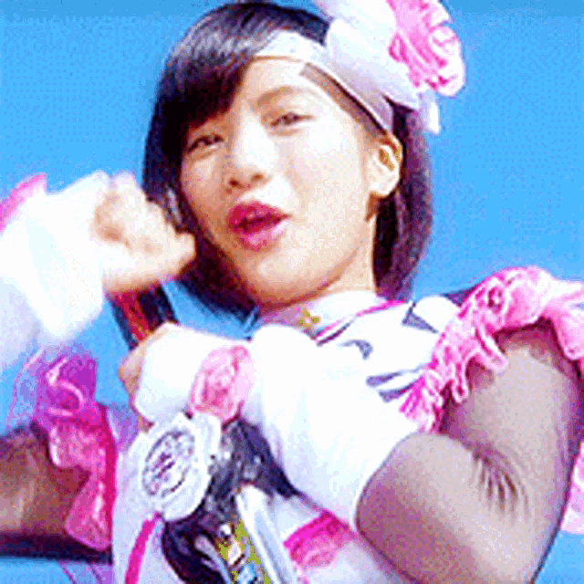 a woman in a pink and white outfit is holding a microphone in her hand