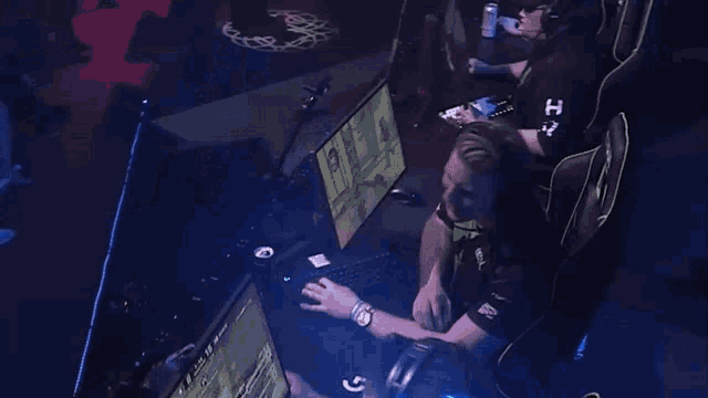 a man wearing headphones is sitting in front of a computer with a can of soda on the table .