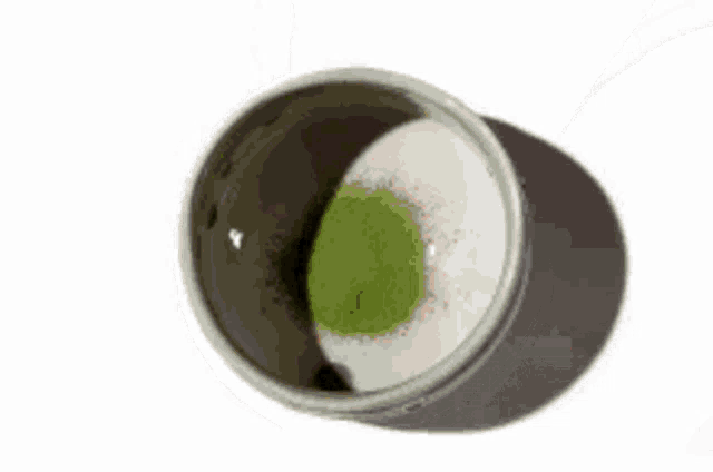 a person is pouring a cup of green tea into a cup .
