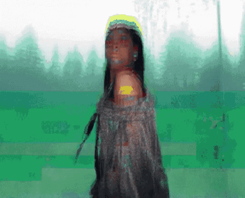 a woman in a native american outfit stands in front of a green forest
