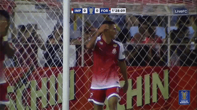 a soccer player stands in front of a net with a scoreboard that says imp 0 and for 1