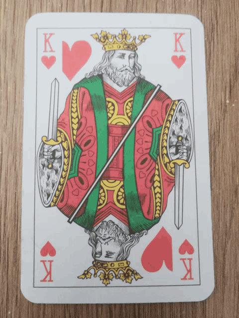 a king of hearts playing card with two swords and a shield