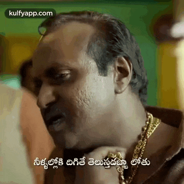 a man wearing a gold chain around his neck is making a funny face in a movie .