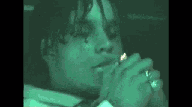 a close up of a person smoking a cigarette with a green background