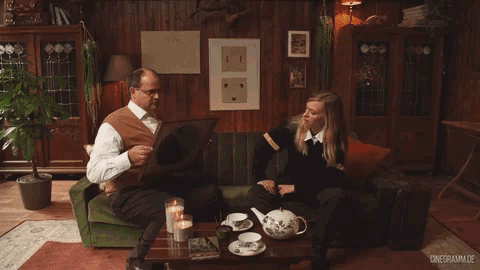 a man is holding a framed picture of a woman while sitting on a couch