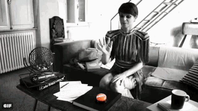 a black and white photo of a woman sitting on a couch next to a table with a button that says happy