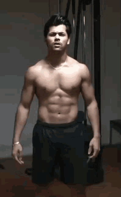 a shirtless man in shorts is standing in a gym .