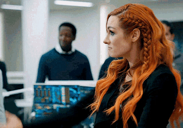 a woman with red hair is standing in front of a laptop computer