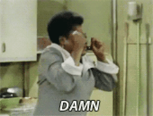 a woman is talking on a cell phone in a kitchen and the word damn is on the screen .