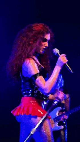 a woman is singing into a microphone while playing a guitar