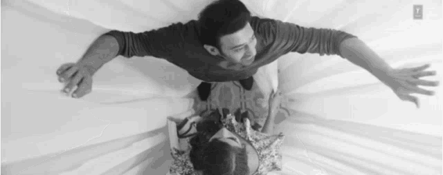 a man and a woman are laying on a bed looking up at each other .