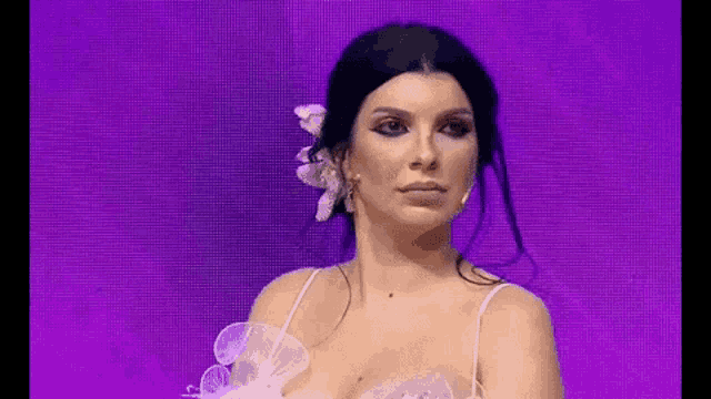 a woman in a white dress is standing in front of a purple background .